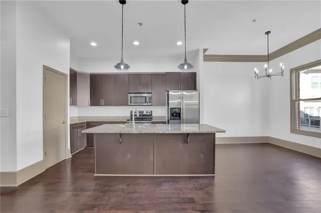 a large kitchen with granite countertop a sink a counter space appliances and cabinets