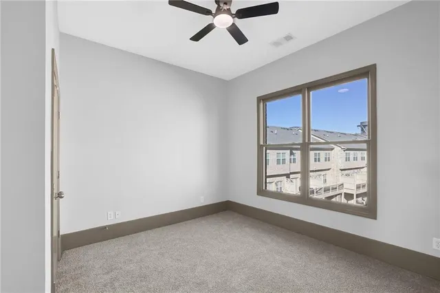 an empty room with windows and ceiling fan