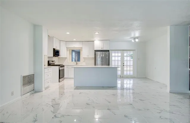 a view of kitchen with kitchen island stainless steel appliances refrigerator sink and cabinets