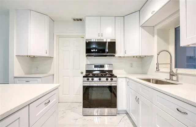 a kitchen with granite countertop a stove a sink and a microwave