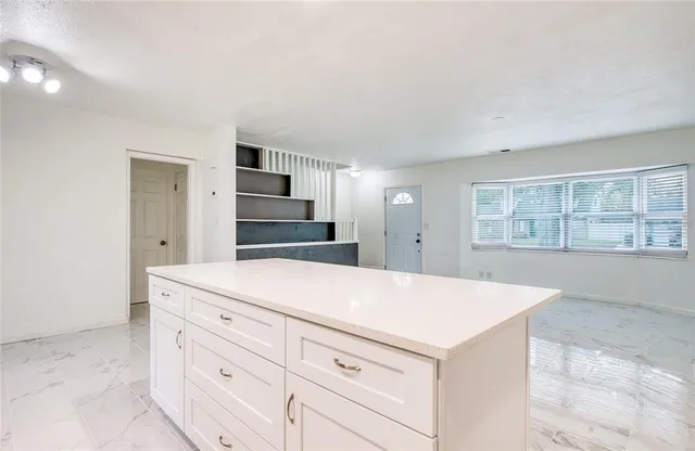 a kitchen with granite countertop white cabinets and refrigerator