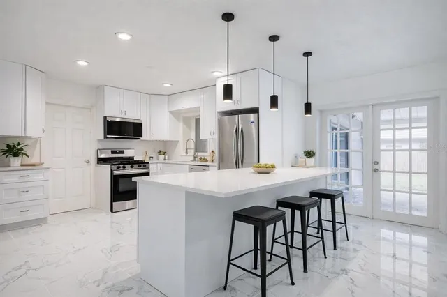 a kitchen with stainless steel appliances kitchen island a table chairs sink and cabinets
