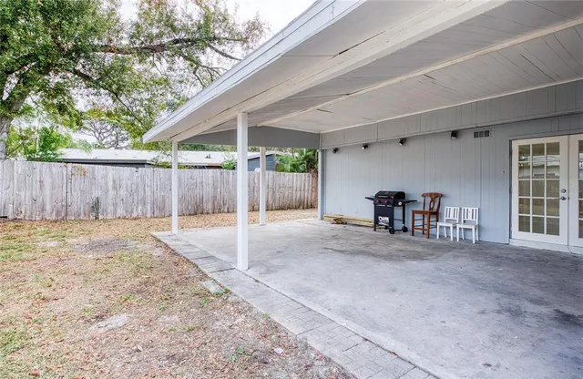 a view of a backyard with wooden fence and a large tree