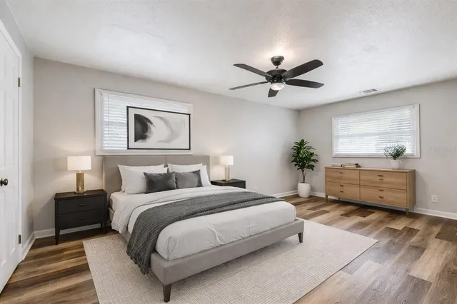 a spacious bedroom with a bed a dresser and a chandelier