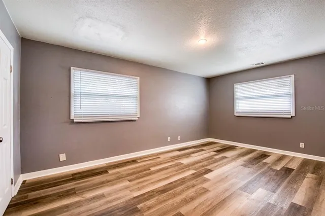 a view of a bedroom with wooden floor and windows