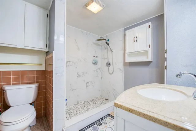 a bathroom with a granite countertop sink a toilet and shower