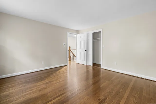 a view of an empty room with wooden floor and closet
