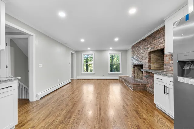 an empty room with wooden floor and a kitchen