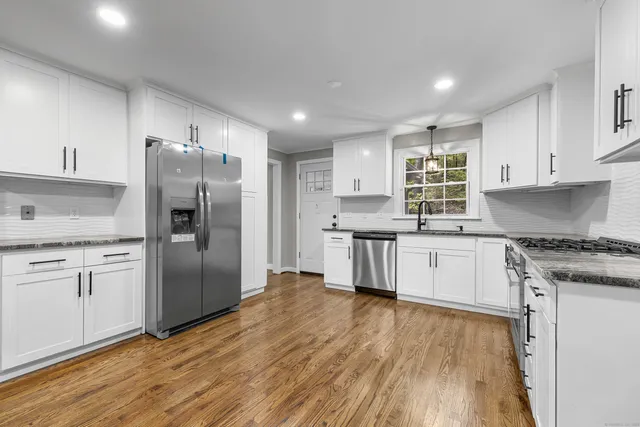 a kitchen with granite countertop a refrigerator stove top oven and sink