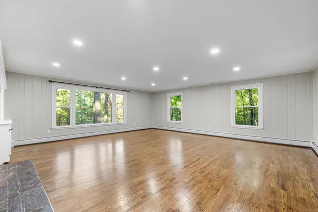an empty room with wooden floor and windows