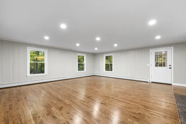 an empty room with wooden floor and windows