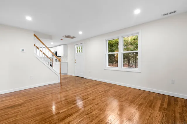 a view of an empty room with wooden floor and stairs