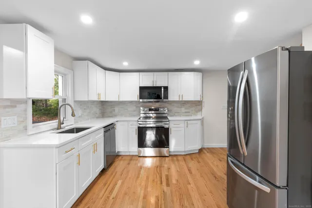 a kitchen with stainless steel appliances granite countertop a refrigerator a stove a sink and a microwave