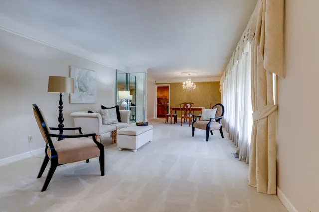 a living room with furniture and a dining table with chair next to a window