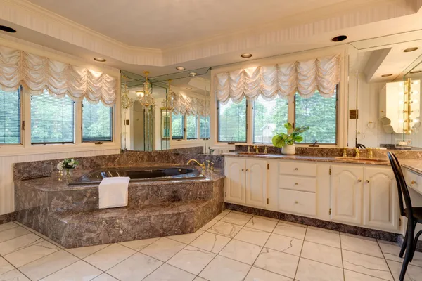 a bathroom with a tub a sink a mirror and a shower