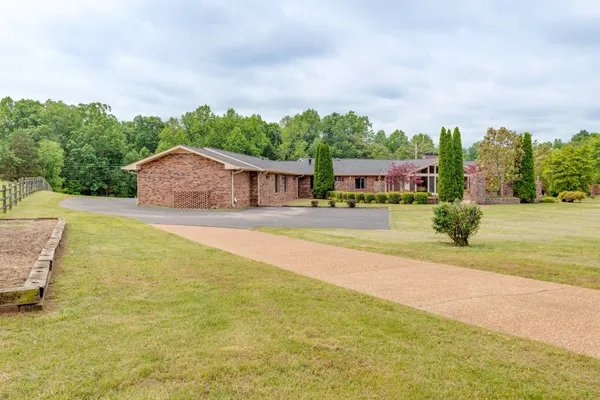 a front view of house with yard and trees in the background