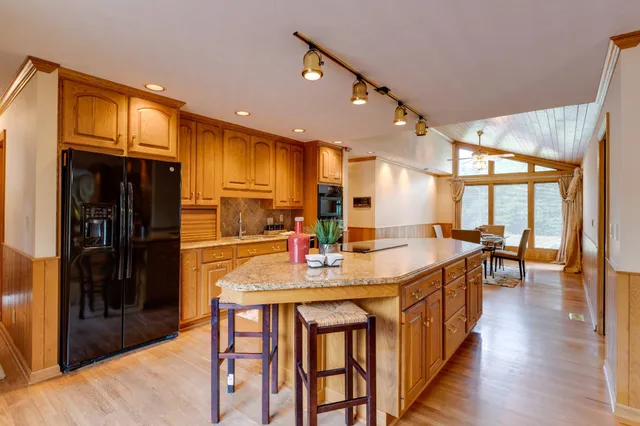 a kitchen with stainless steel appliances kitchen island granite countertop a table chairs and a refrigerator