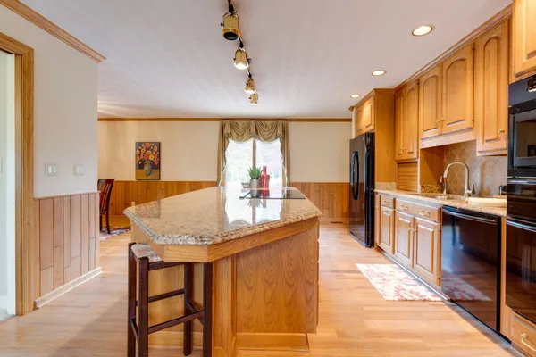 a kitchen with stainless steel appliances granite countertop table chairs and a large window