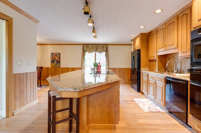 a kitchen with stainless steel appliances granite countertop table chairs and a large window