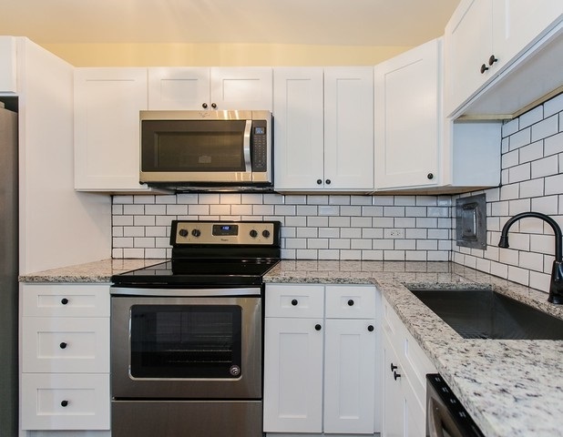 5757 North Sheridan Road, Unit 9C Chicago, IL 60660 - Photo 4 of 25 a kitchen with granite countertop a stove top oven microwave and cabinets