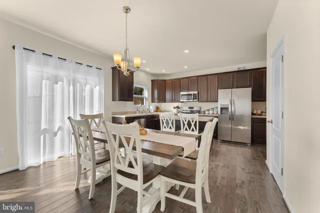 a kitchen with stainless steel appliances a dining table chairs refrigerator and microwave