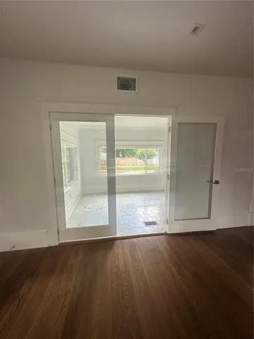 an empty room with wooden floor and windows
