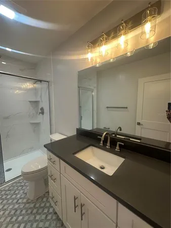 a bathroom with a granite countertop sink toilet a large mirror and shower