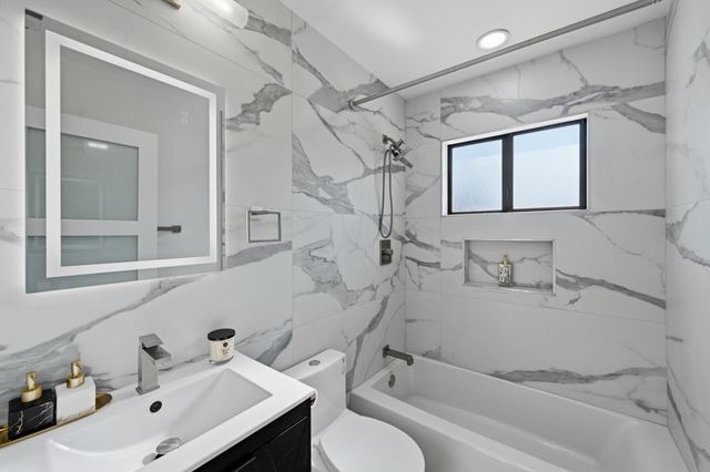 a bathroom with a sink vanity mirror and tub
