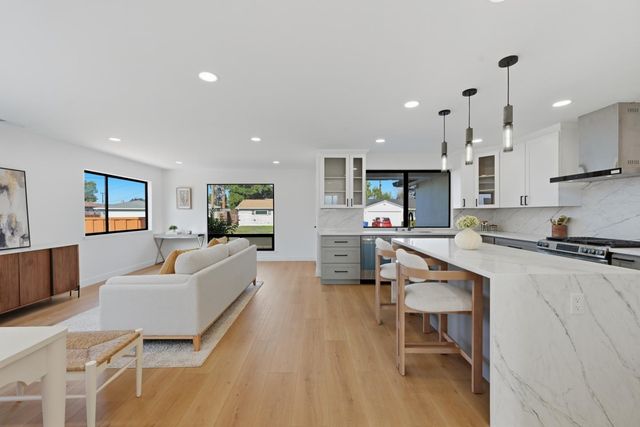 a living room with stainless steel appliances kitchen island granite countertop furniture and a wooden floor