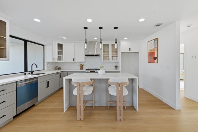 a kitchen with stainless steel appliances granite countertop a table chairs sink refrigerator and cabinets