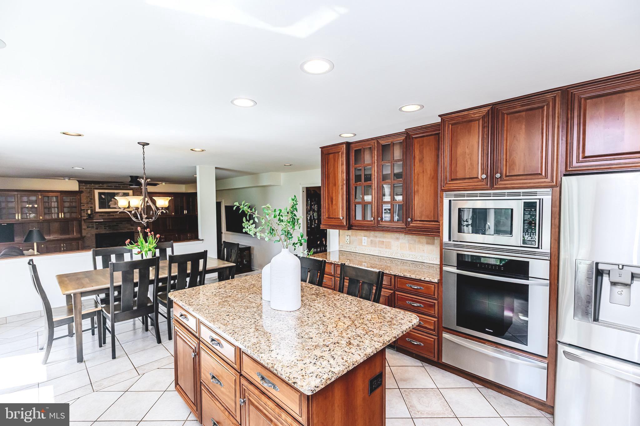 680 Fox Hollow Drive Yardley, PA 19067 - Photo 13 of 63 a kitchen with stainless steel appliances kitchen island granite countertop a table chairs and a refrigerator