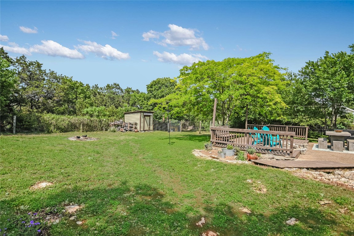 6802 Rio Bravo Lane Austin, TX 78737 - Photo 18 of 18 Fenced backyard featuring a wooden deck, a storage shed, and an outdoor fire pit