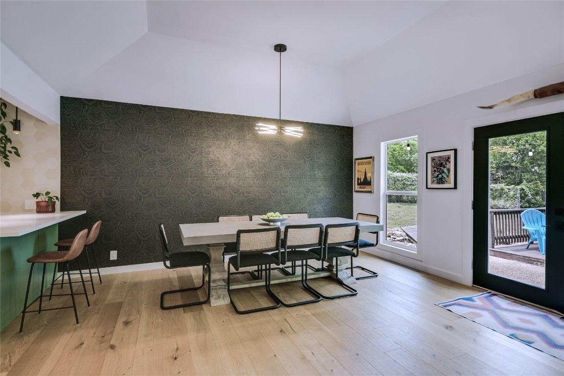 6802 Rio Bravo Lane Austin, TX 78737 - Photo 7 of 18 Dining room featuring wallpapered walls, vaulted ceiling, light wood finished floors, and an accent wall