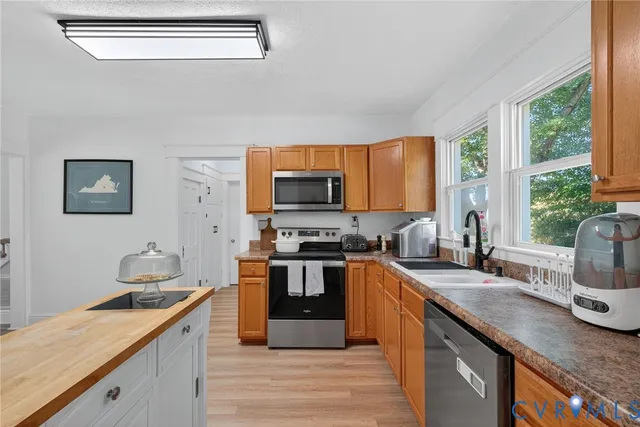 a kitchen with stainless steel appliances granite countertop a stove a sink dishwasher and wooden cabinets with wooden floor