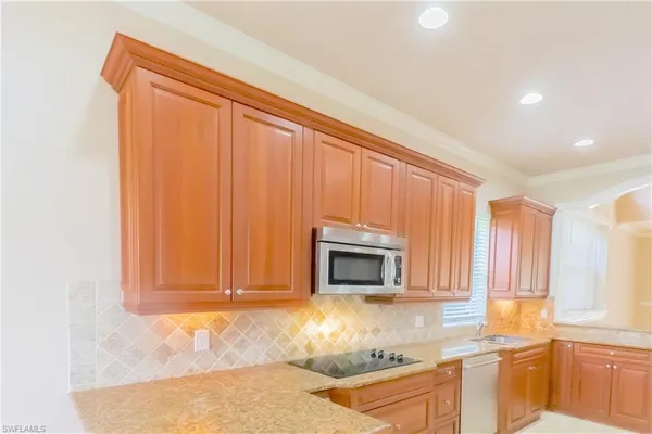 a kitchen with granite countertop cabinets stainless steel appliances a sink and a window