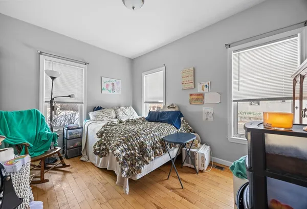 a bedroom with a bed table flowerpot and window