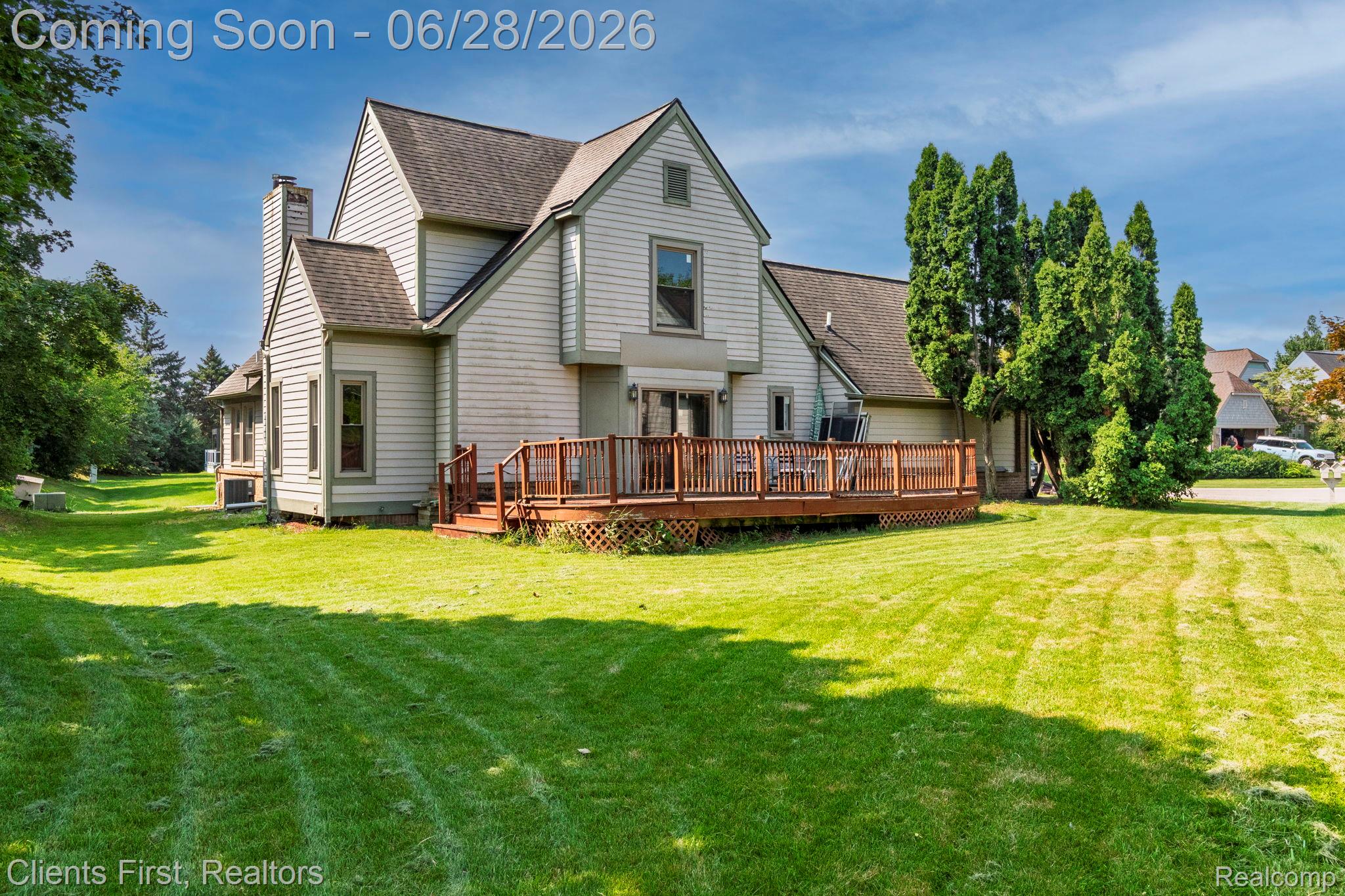 Expansive rear yard featuring a large wooden deck and manicured lawn