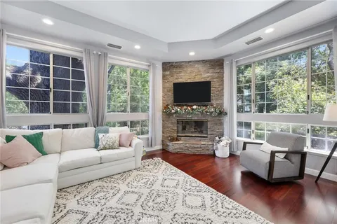 a living room with furniture a fireplace a flat screen tv and a large window
