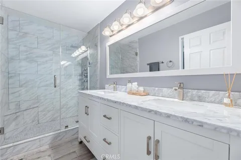 a bathroom with a granite countertop sink a mirror and shower