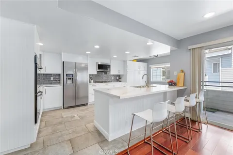 a kitchen with stainless steel appliances kitchen island granite countertop a refrigerator and a sink