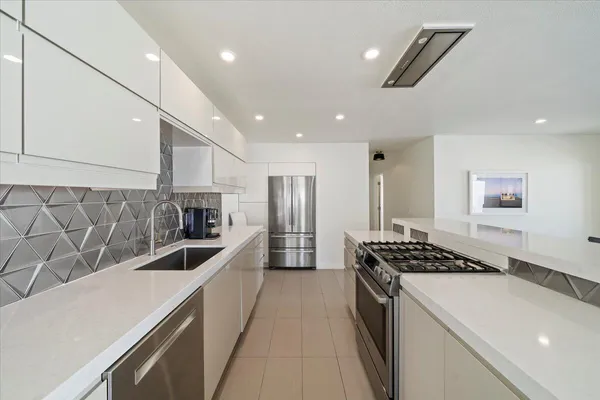 a kitchen with stainless steel appliances granite countertop a sink a stove and a refrigerator