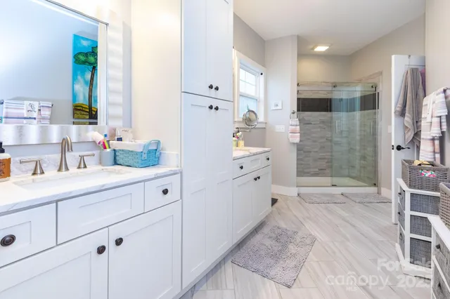 a spacious bathroom with a double vanity sink a mirror and a shower