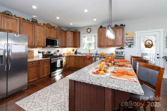 a kitchen with stainless steel appliances granite countertop a stove top oven a sink dishwasher and a refrigerator with wooden floor
