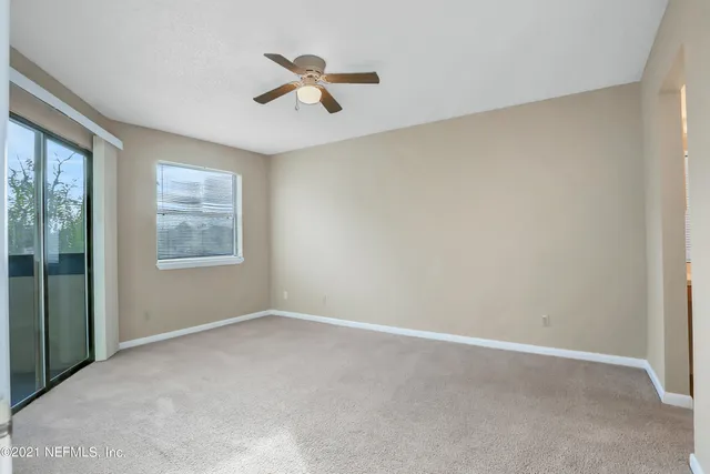 an empty room with windows and fan