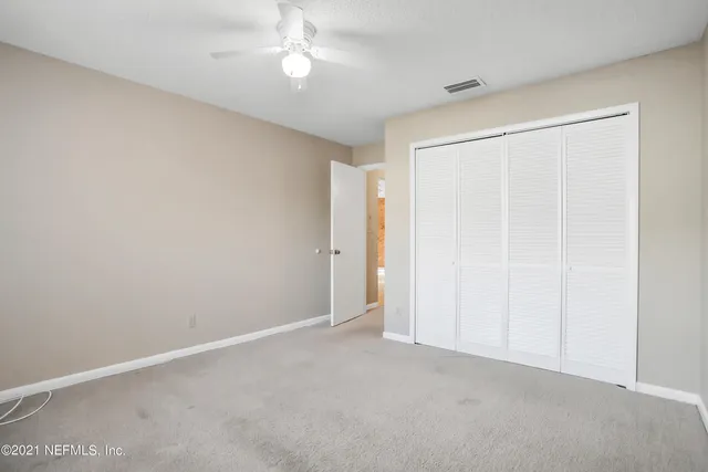 an empty room with a ceiling fan and a window