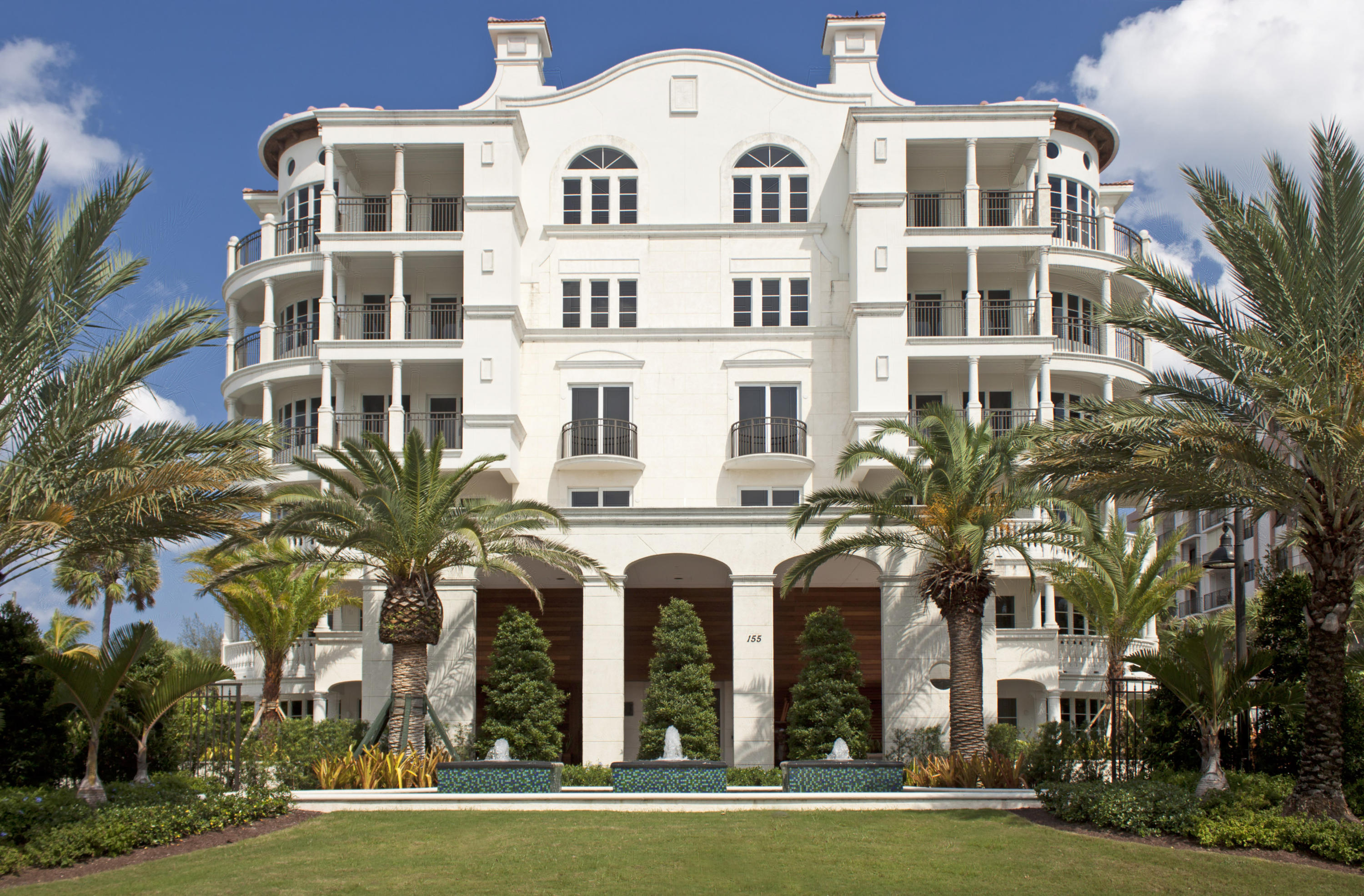 a view of a white building with a clock tower in front of it