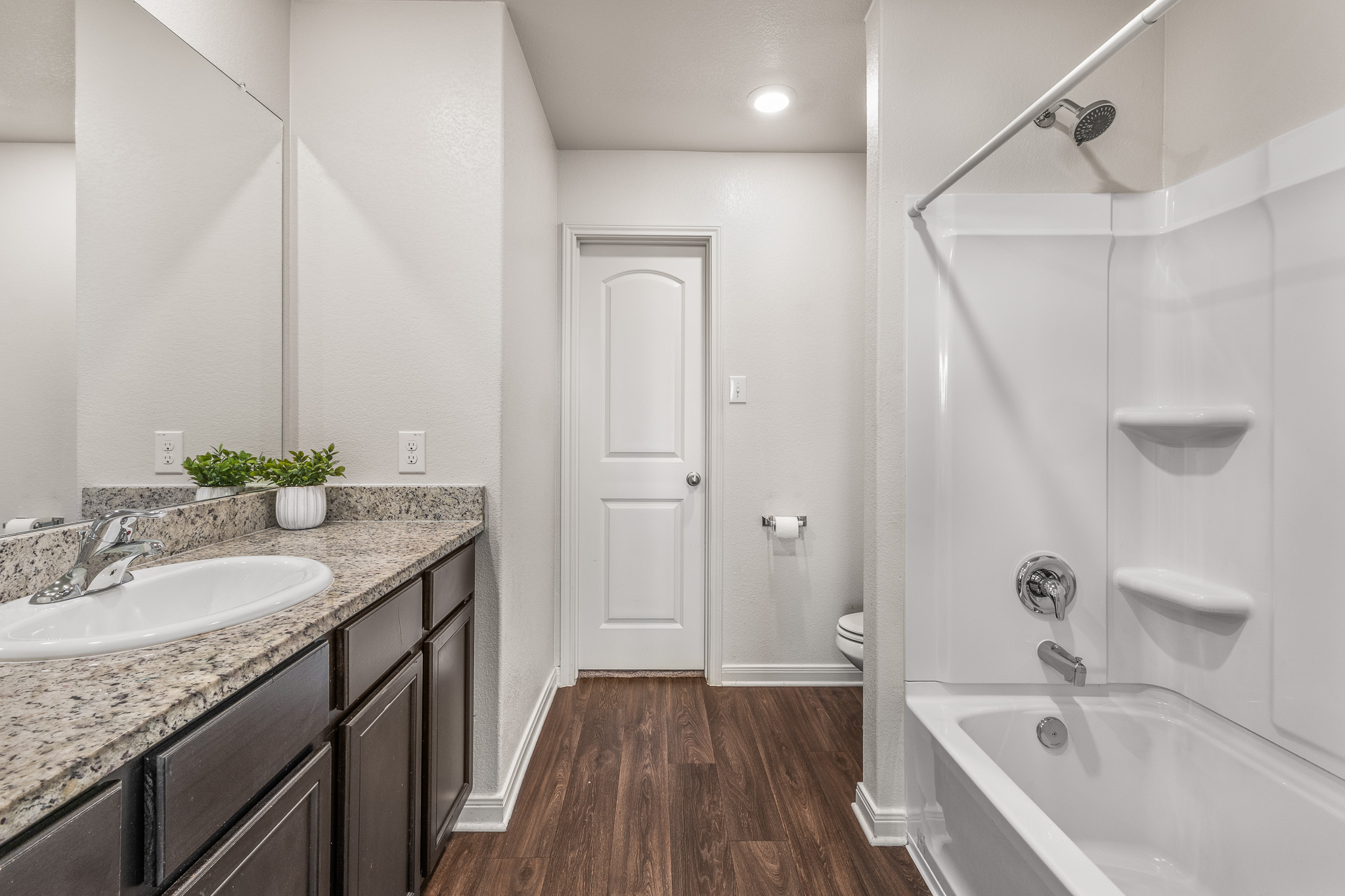 304 Hyacinth Way, Unit #7K Jarrell, TX 76537 - Photo 14 of 26 Granite counters and wood-look flooring enhance this crisp, clean primary bathroom.