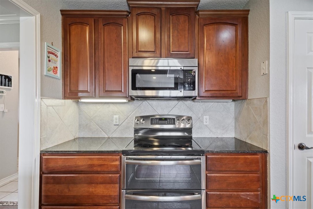 8600 Five Wells Road Rogers, TX 76569 - Photo 15 of 47 a kitchen with granite countertop wood cabinets and stainless steel appliances