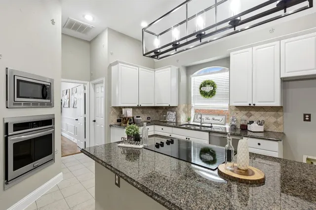 a kitchen with stainless steel appliances granite countertop a sink a stove and cabinets