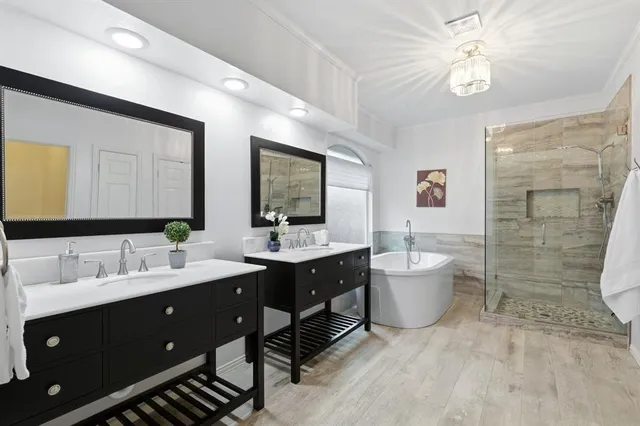 a spacious bathroom with a double vanity sink a large mirror and a bathtub